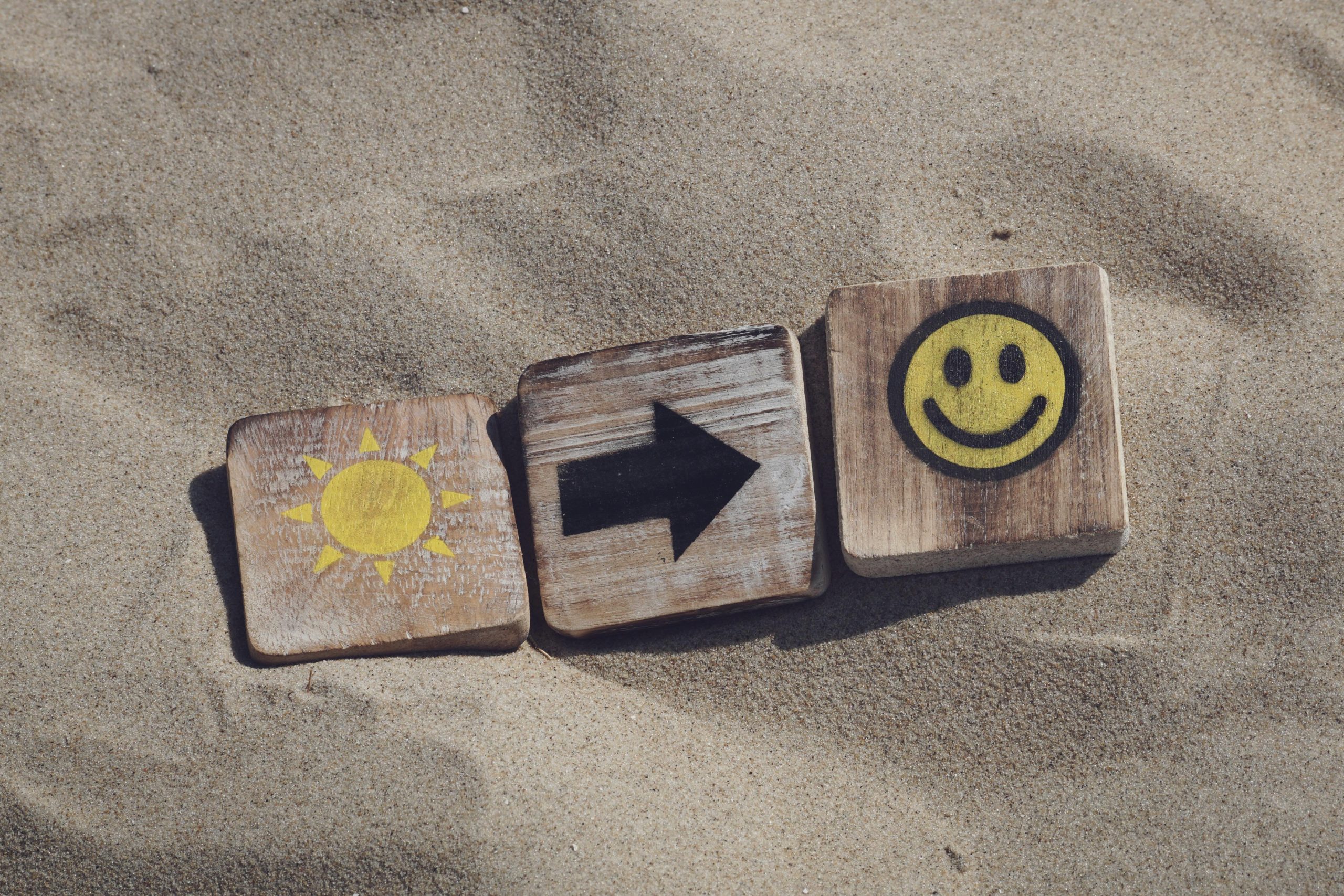 sable fin, 3 cubes en bois avec des dessins dessus (1 soleil, 1 flèche, 1 émoji sourire)